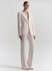 Woman wearing a light pink suit on a plain background