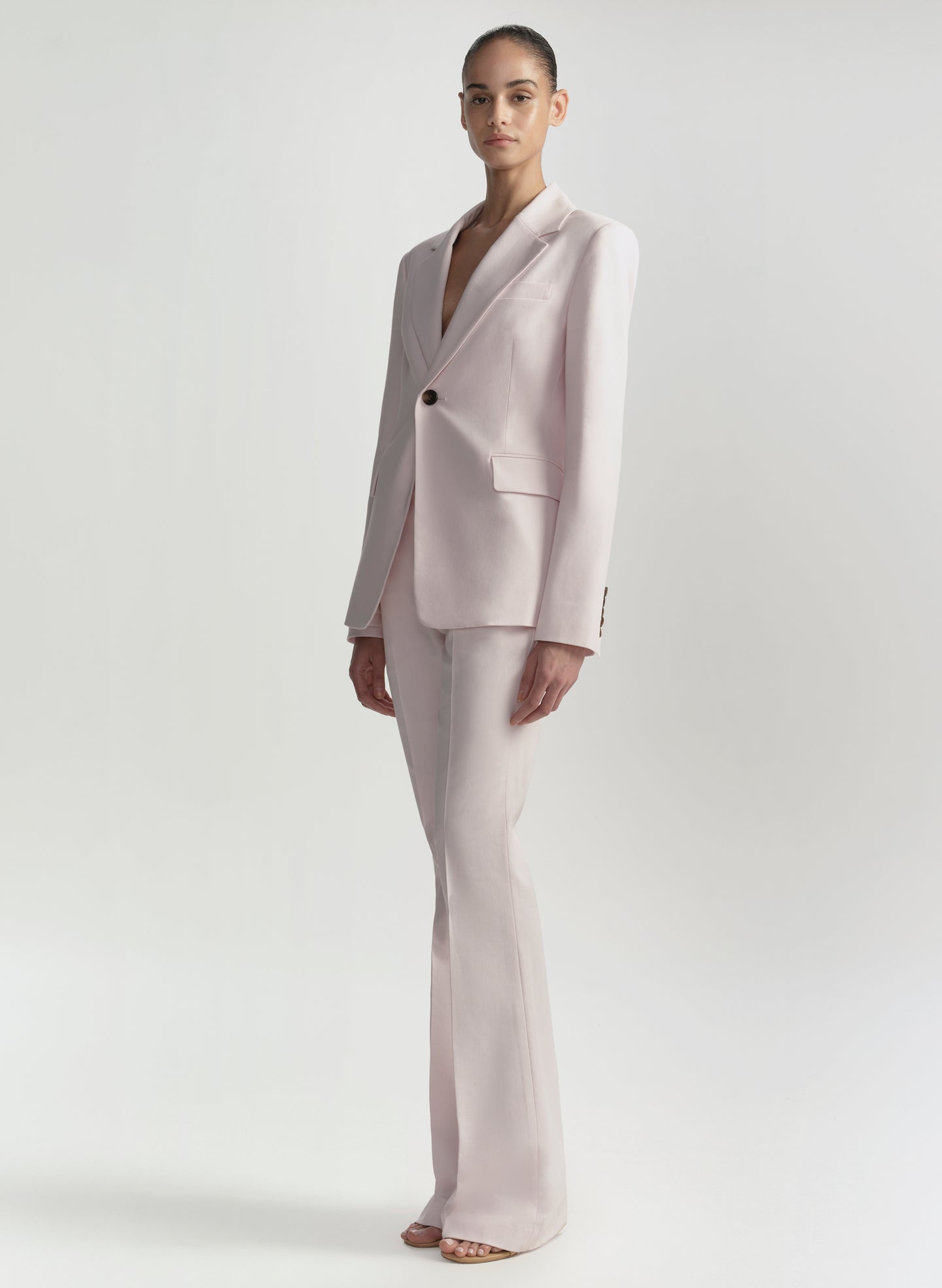 Woman wearing a light pink suit on a white background