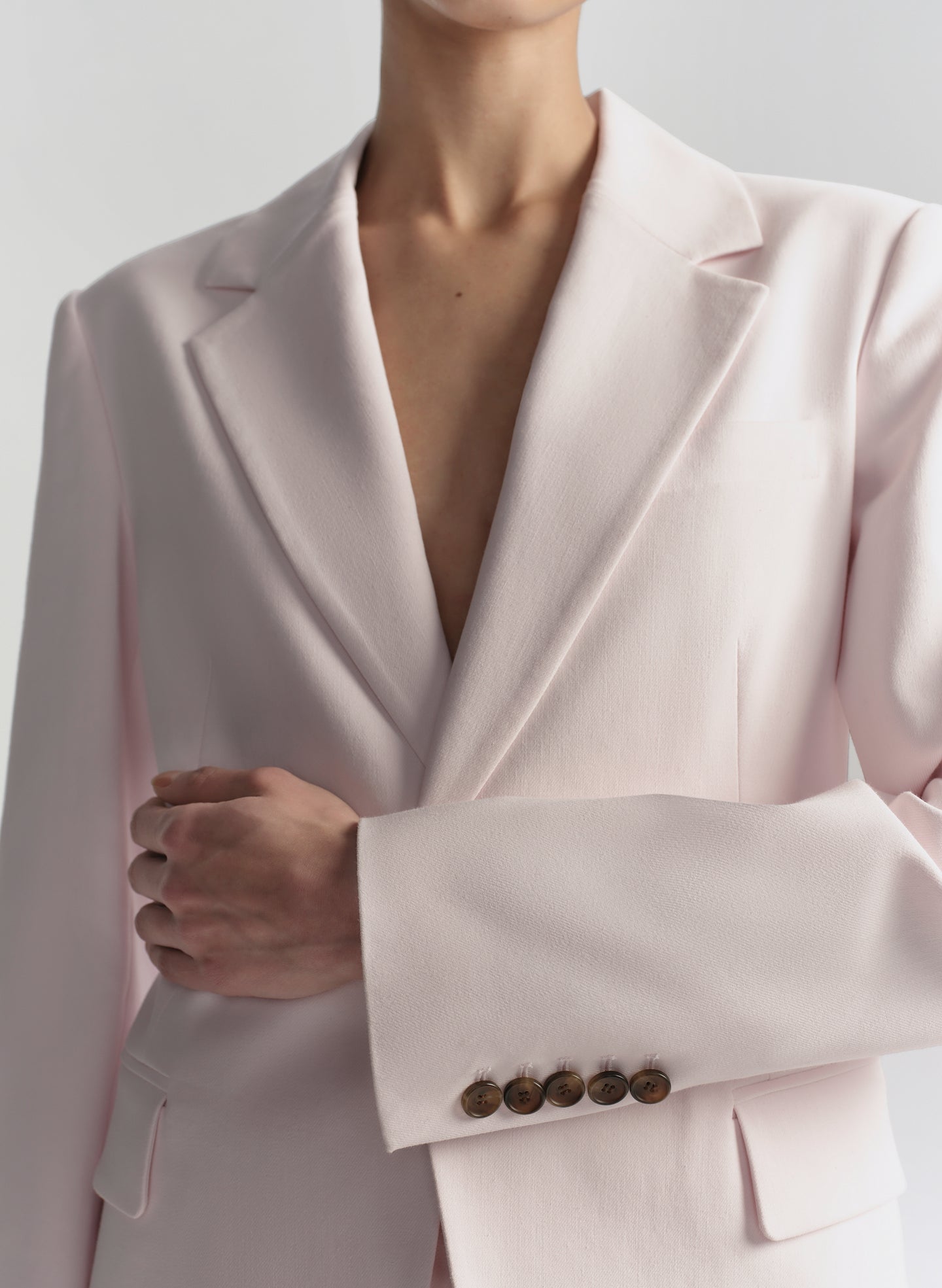 Close-up of a light pink blazer with a plain background