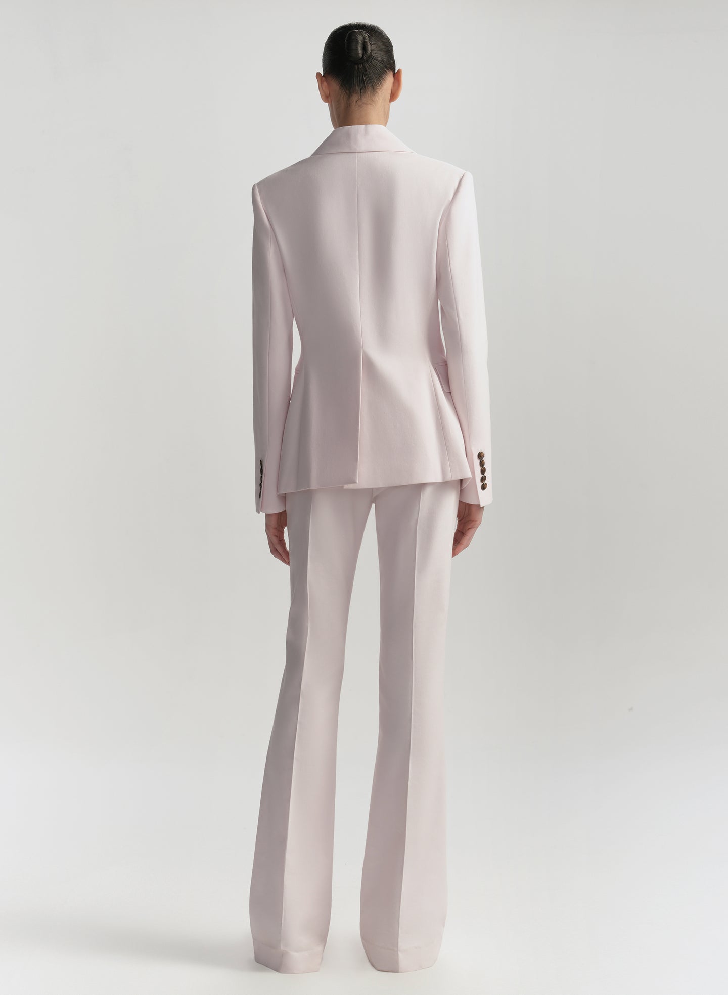 Person wearing a light pink suit on a white background