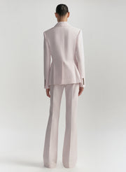 Person wearing a light pink suit on a white background