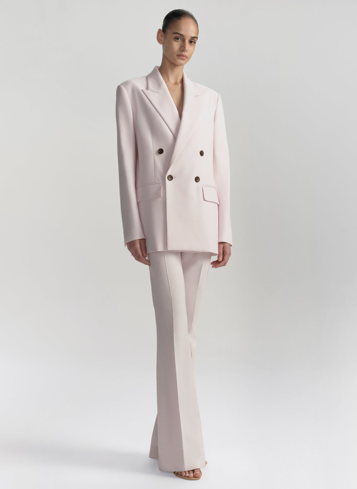 Woman wearing a light pink suit on a white background