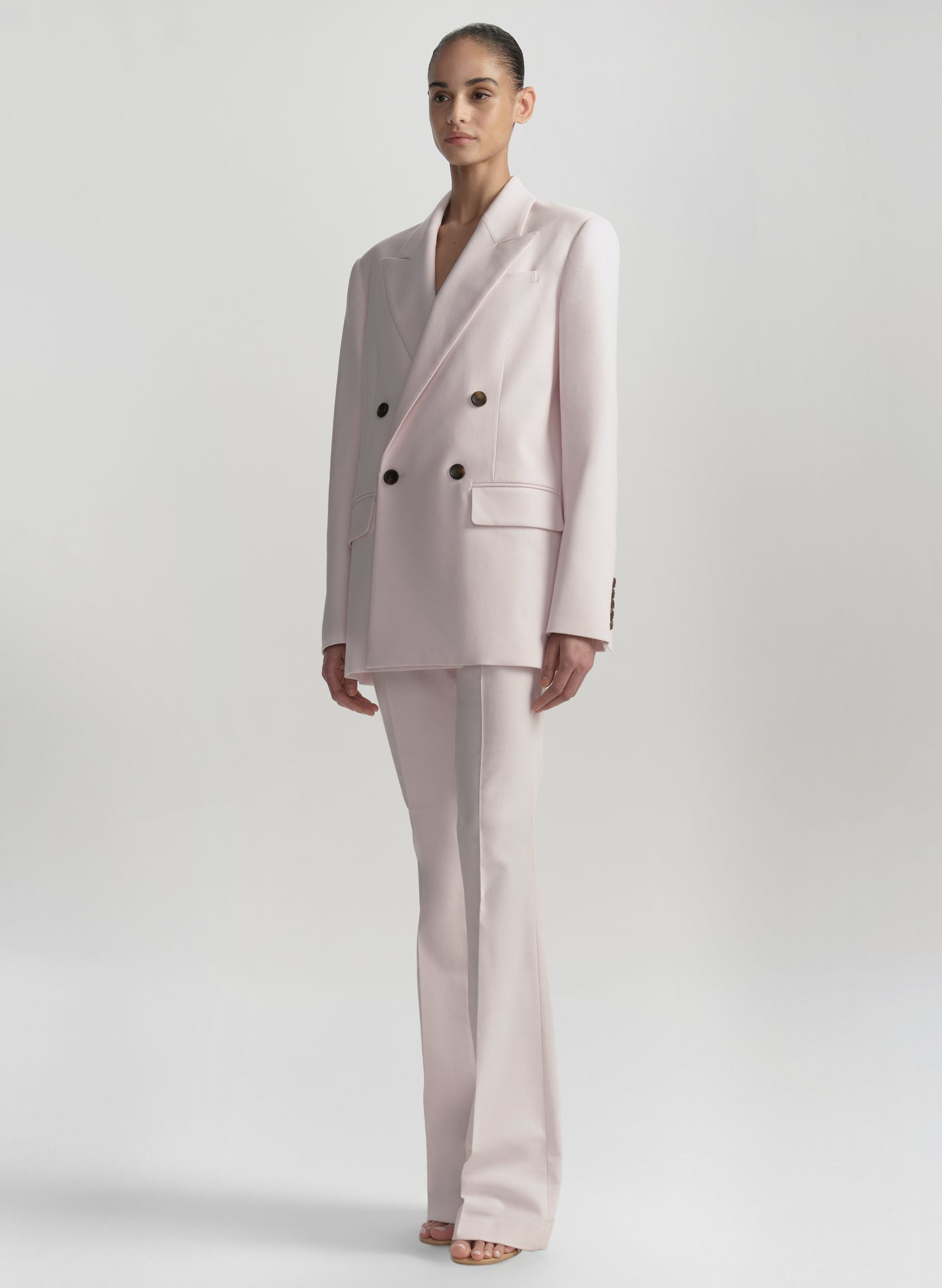 Woman wearing a light pink suit on a white background