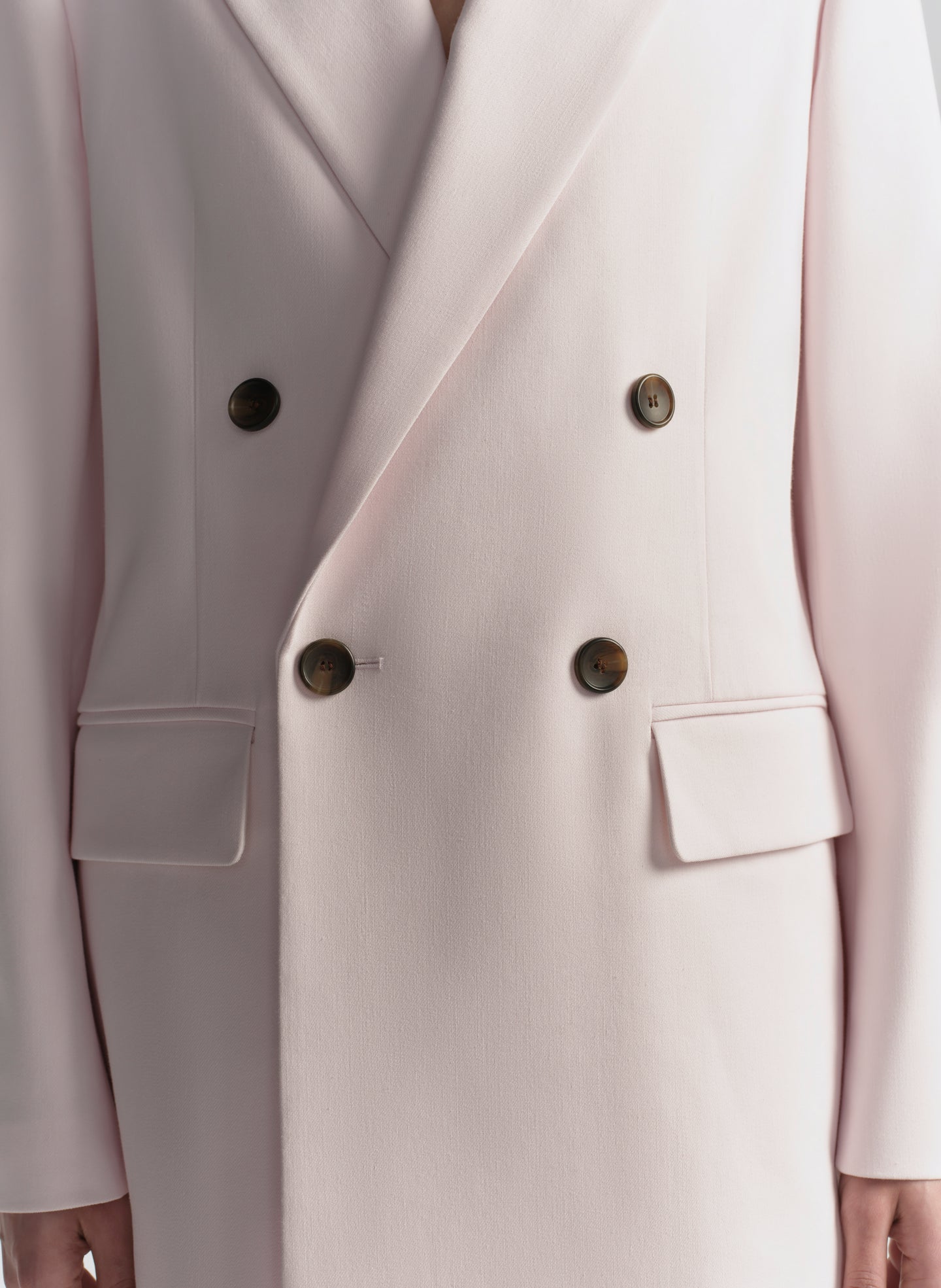 Close-up of a light pink blazer with double-breasted buttons.