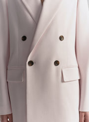 Close-up of a light pink blazer with double-breasted buttons.