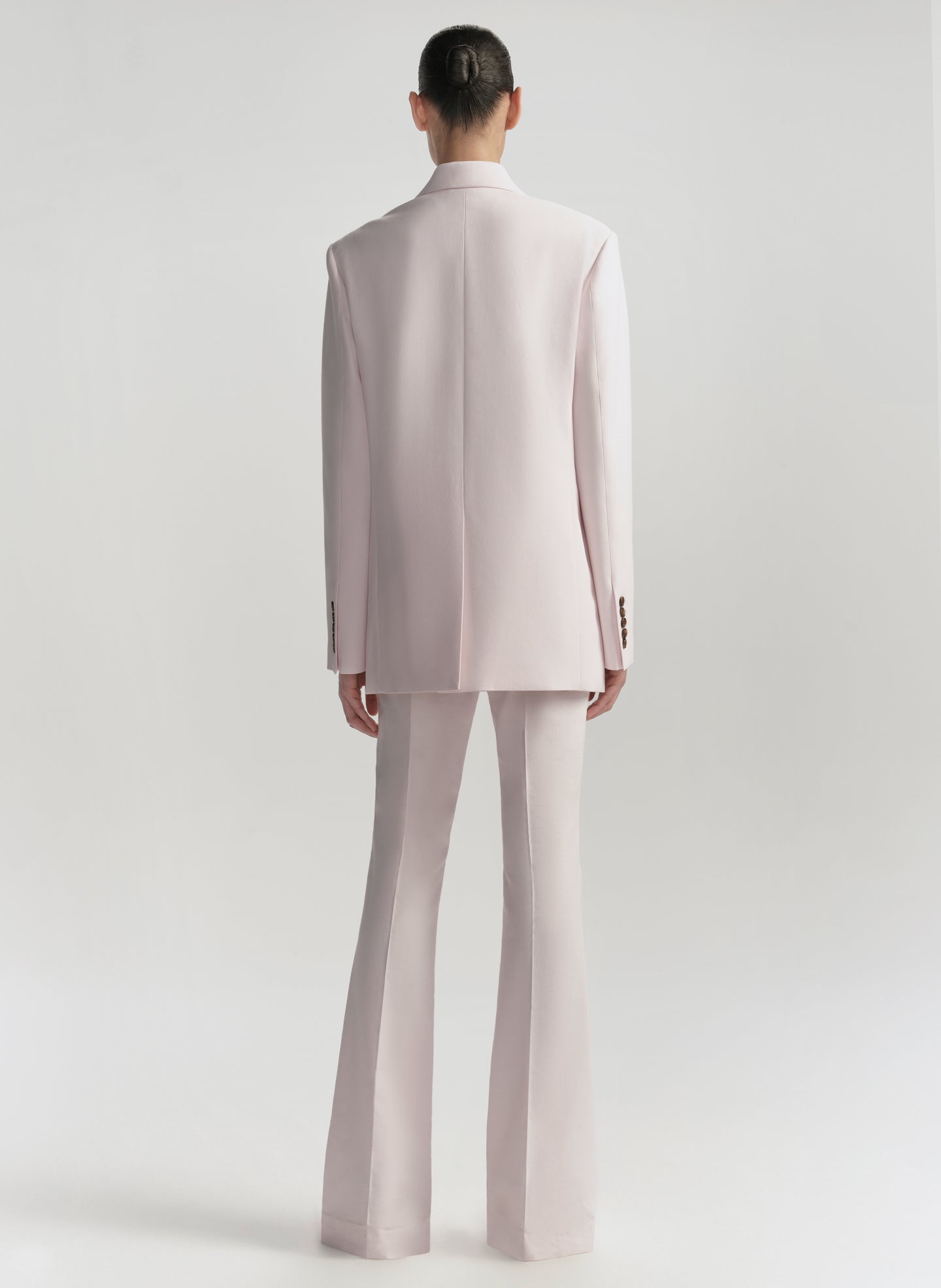 Person wearing a light pink suit on a white background
