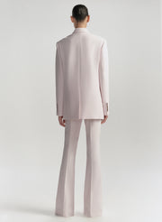 Person wearing a light pink suit on a white background