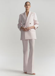Person wearing a light pink suit on a plain background