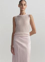 Woman wearing a light pink sleeveless top and skirt on a plain background