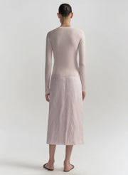 Person wearing a light pink long-sleeve top and skirt set on a white background