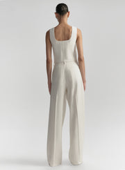 Woman wearing a white sleeveless outfit on a plain background