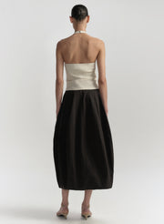 Woman wearing a beige top and black skirt on a white background