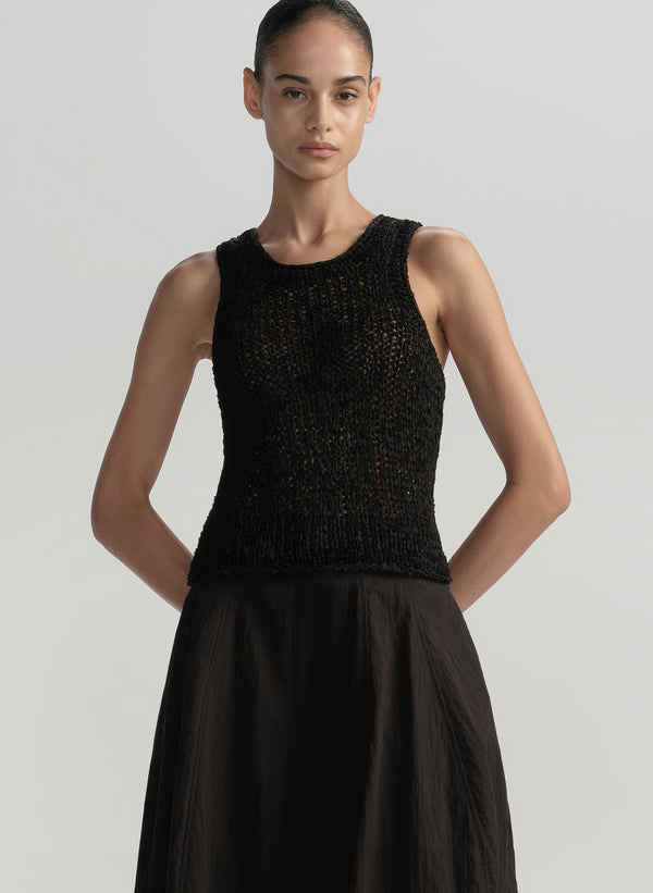 Woman wearing a black sleeveless top and skirt on a plain background