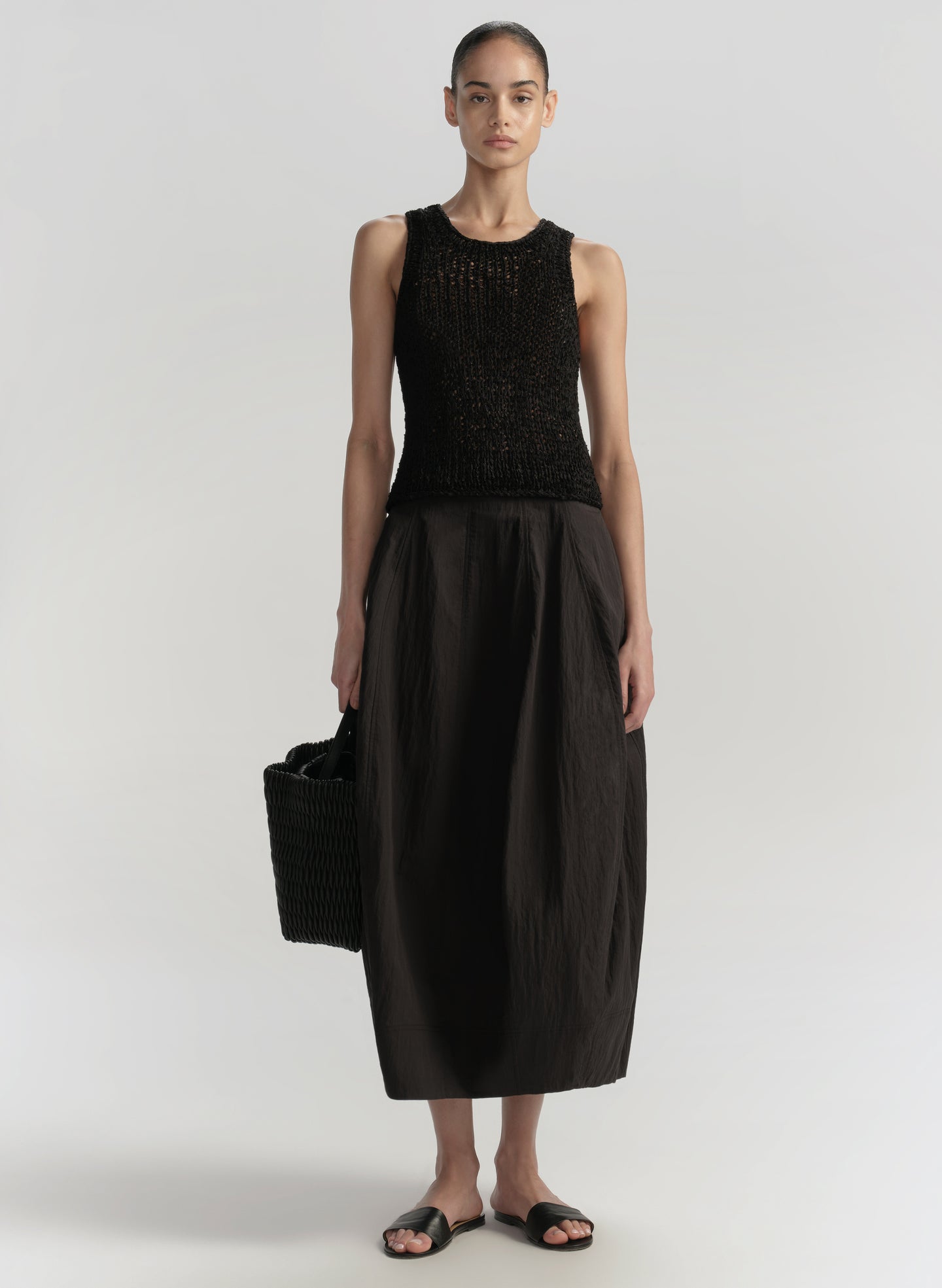 Woman wearing a black sleeveless top and black skirt on a white background