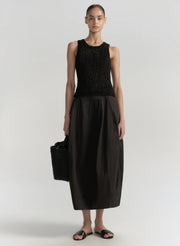 Woman wearing a black sleeveless top and black skirt on a white background