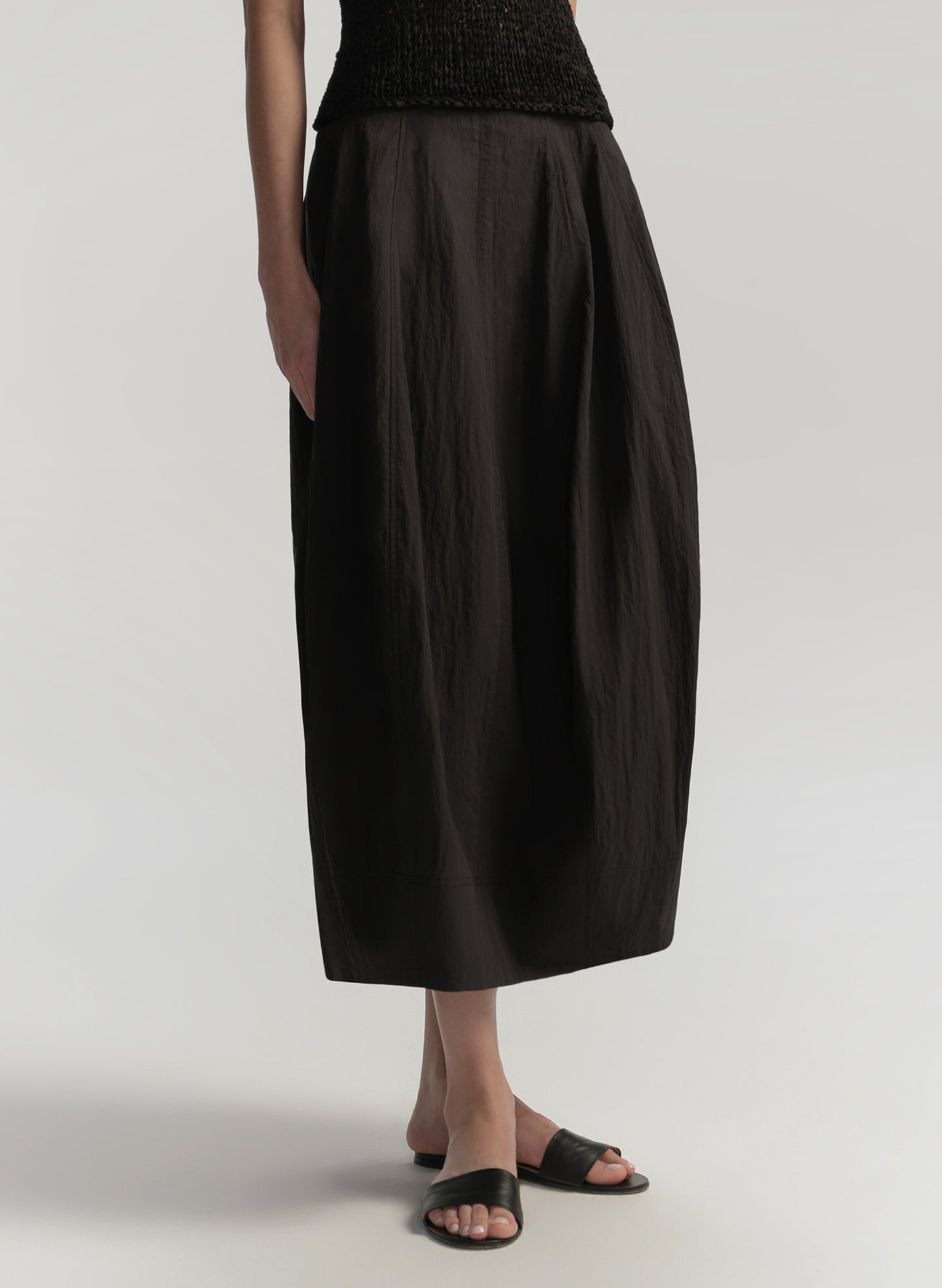 Person wearing a black skirt on a plain background