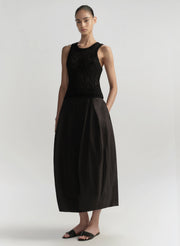 Woman wearing a black sleeveless top and black skirt on a white background