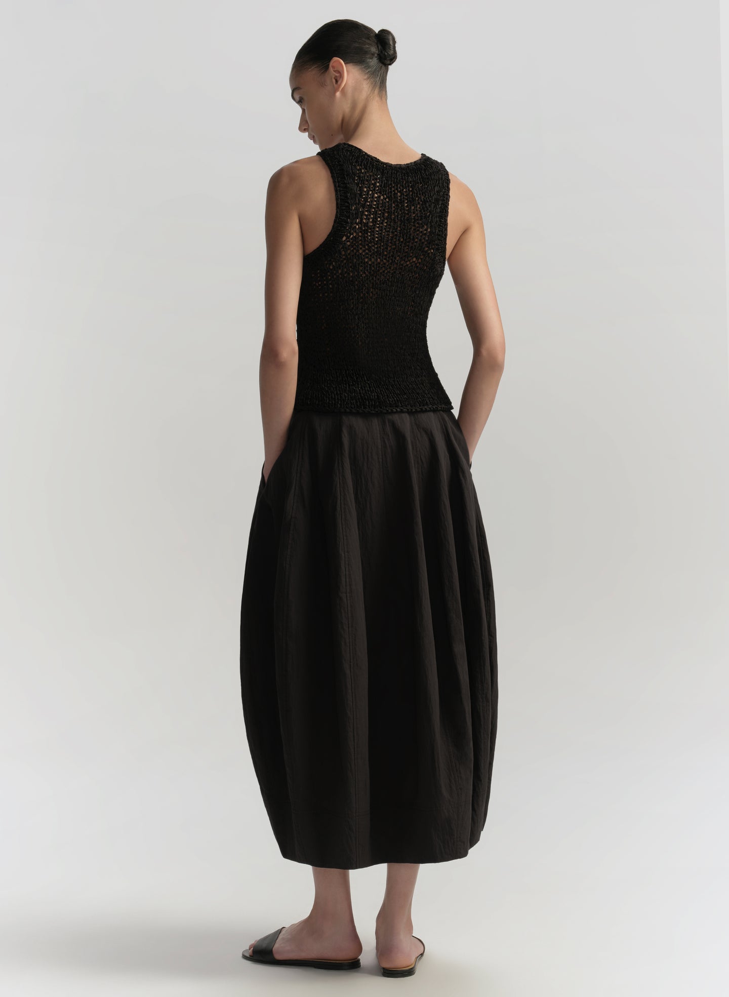 Woman wearing a black sleeveless top and skirt set on a white background