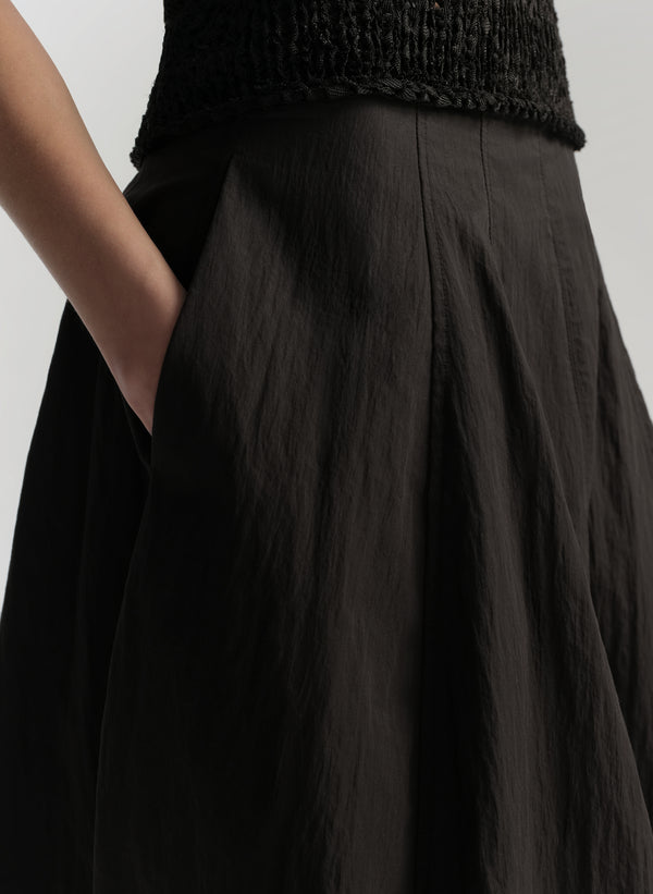 Person wearing a black skirt with a plain background