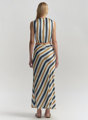 Woman wearing a sleeveless striped top and long skirt on a plain background