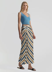 Woman wearing a blue top and striped skirt on a light gray background