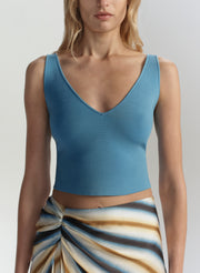 Woman wearing a blue tank top against a plain background