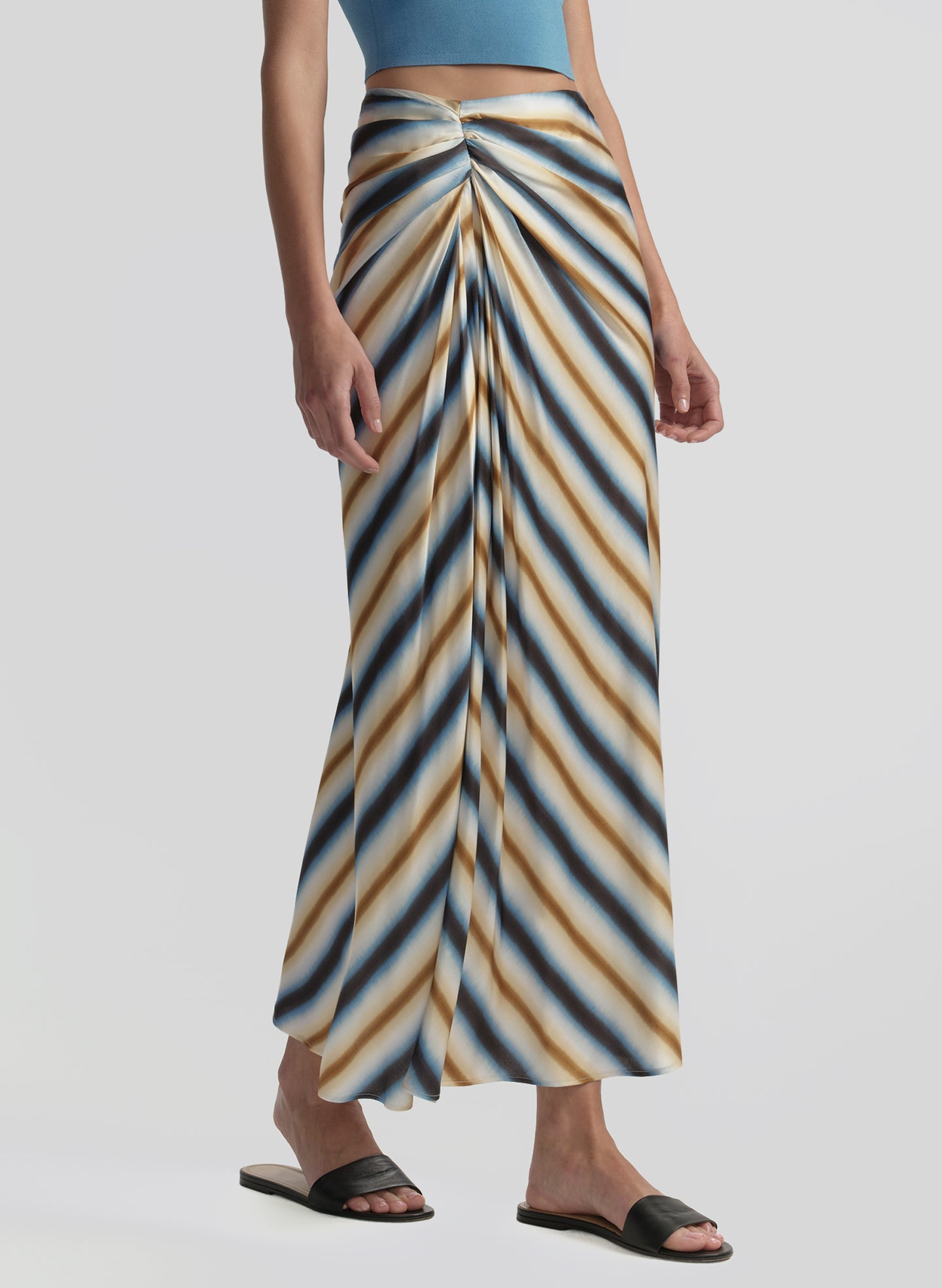 Person wearing a long, patterned skirt with a plain background