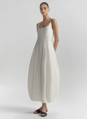 Woman wearing a white sleeveless dress against a plain background