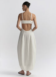 Woman wearing a white dress with an open back on a plain background