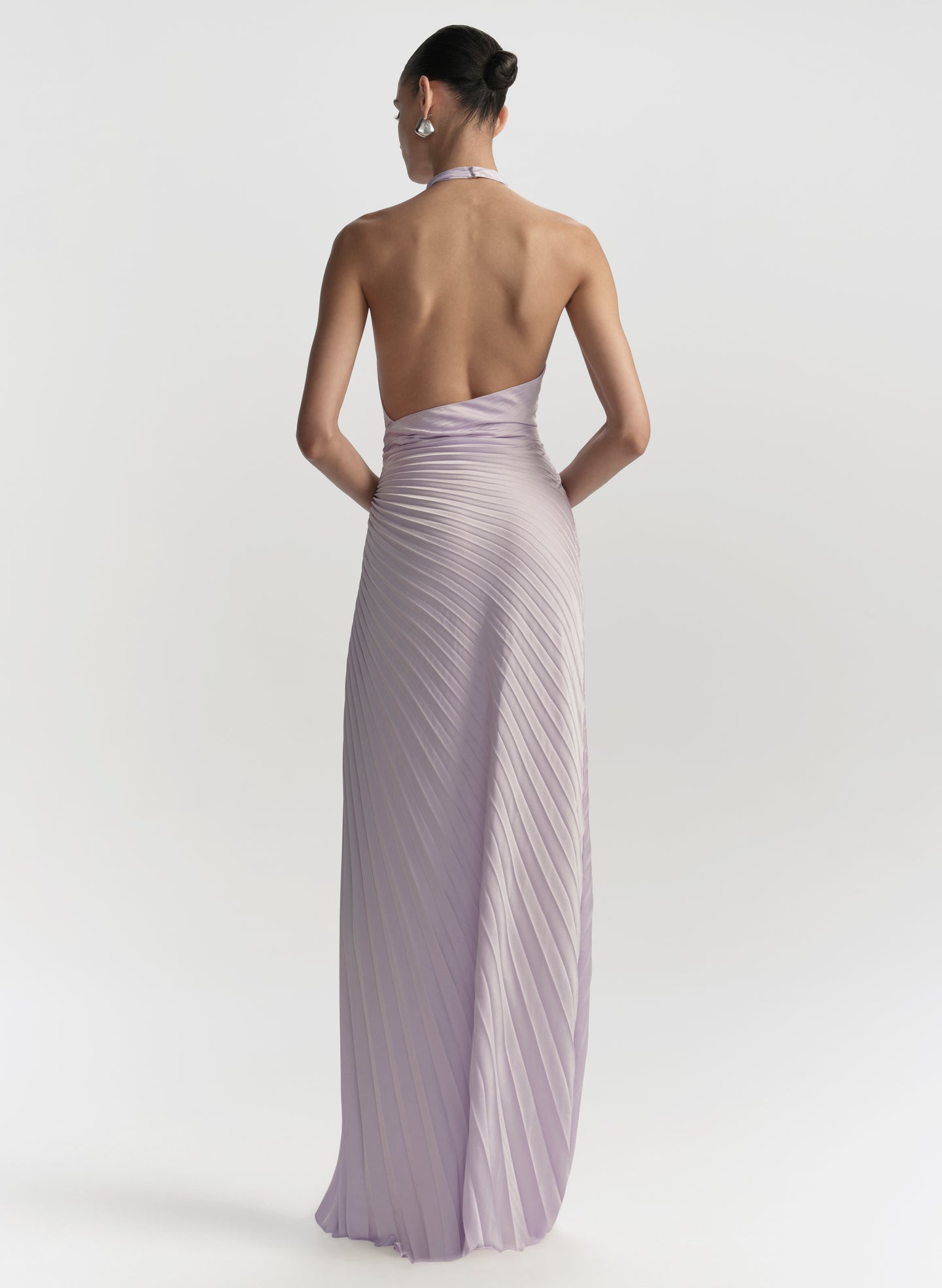 Woman wearing a long, light purple dress with a pleated design on a white background