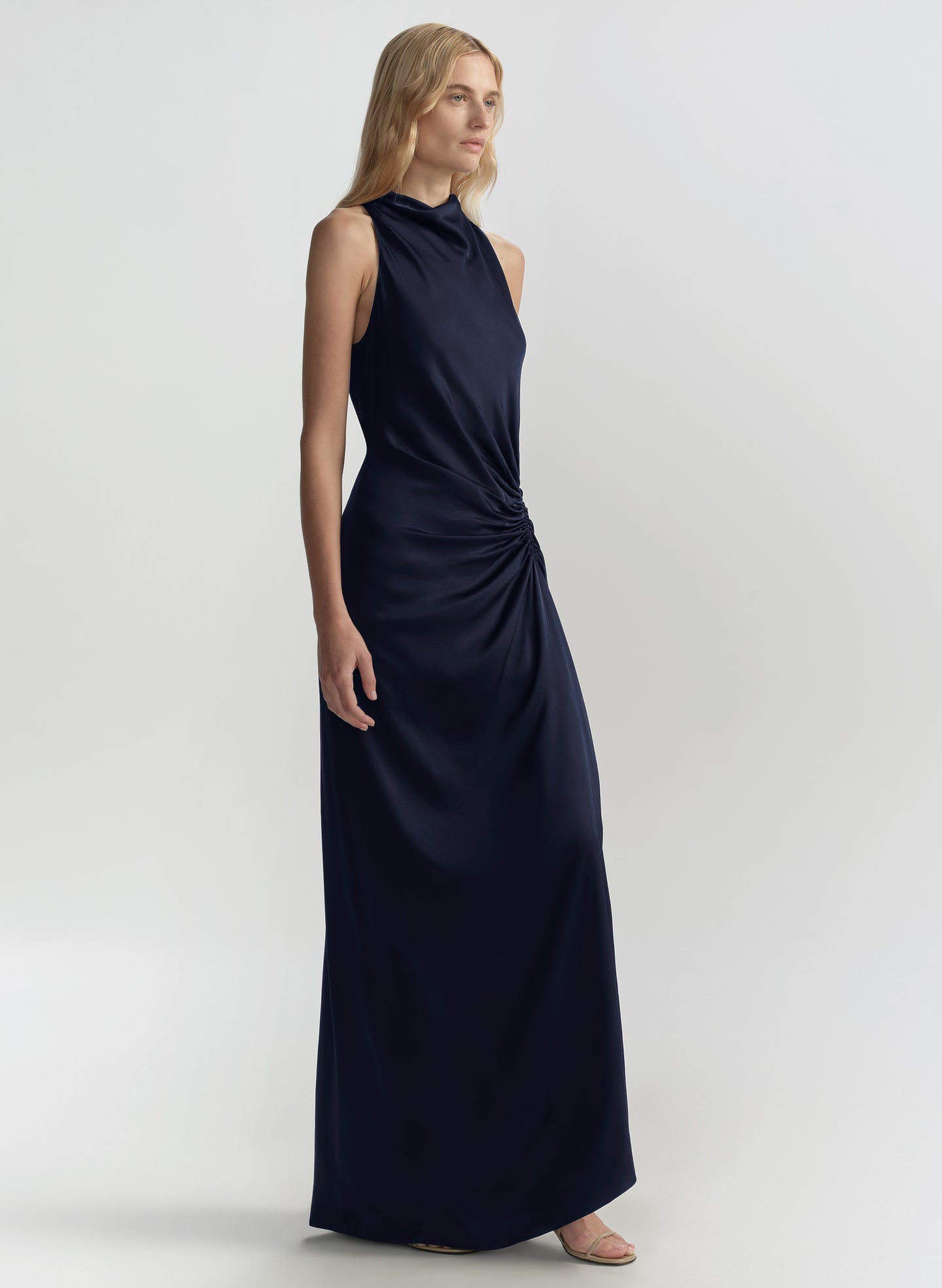 Woman wearing a navy blue halter neck gown on a light gray background