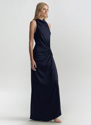 Woman wearing a navy blue halter neck gown on a light gray background