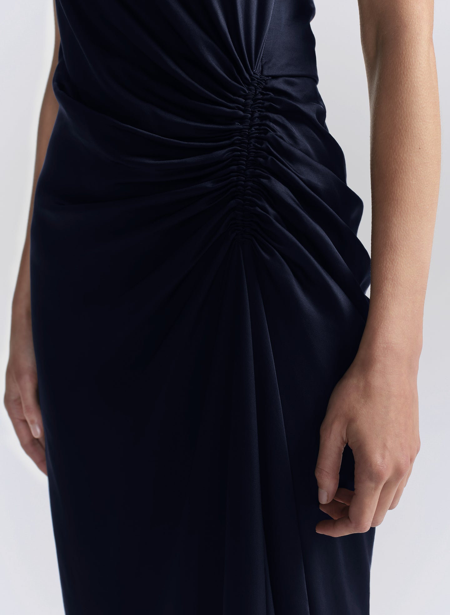 Woman wearing a navy blue halter neck gown on a light gray background