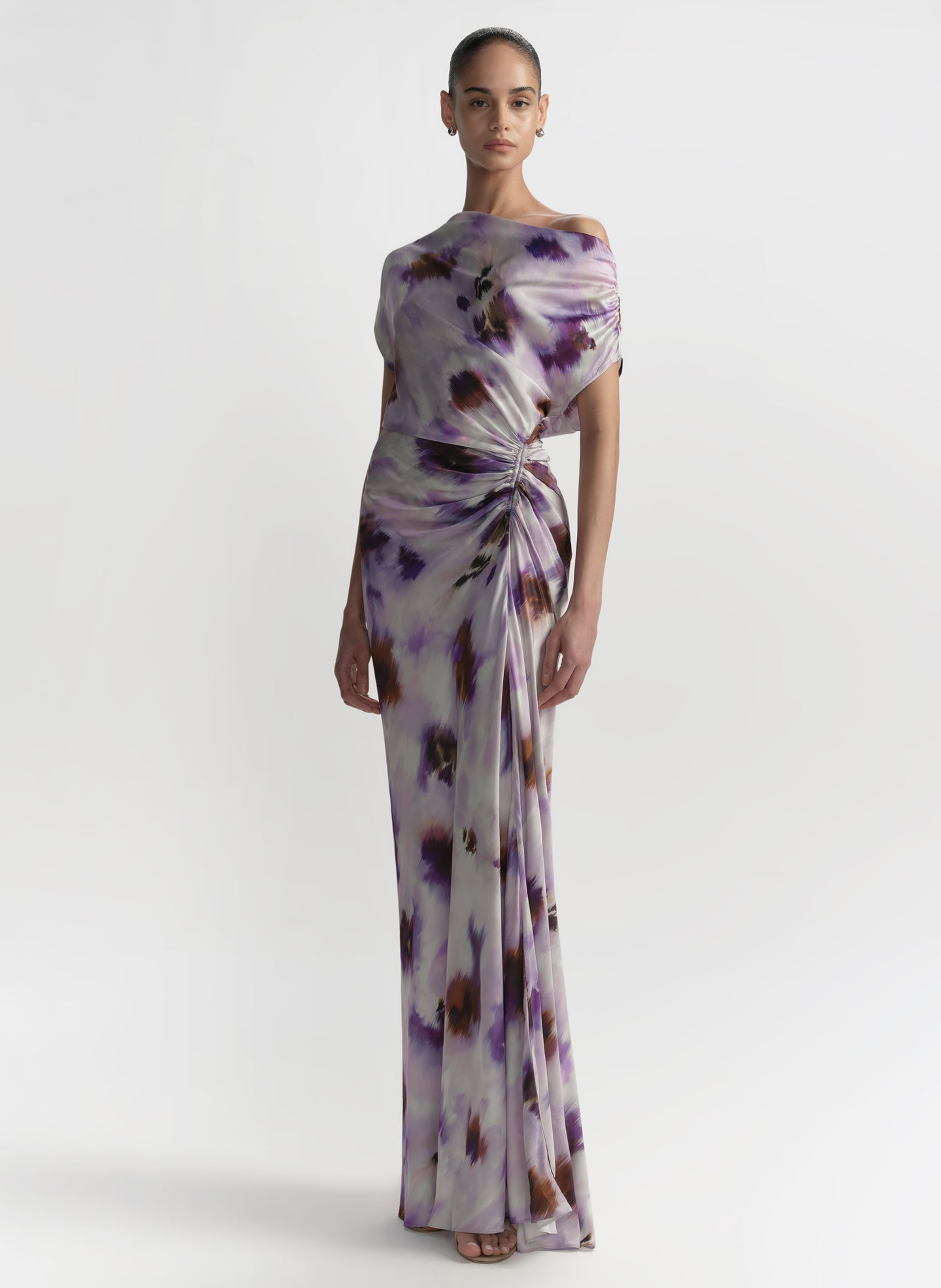 Woman wearing a floral one-shoulder gown on a white background