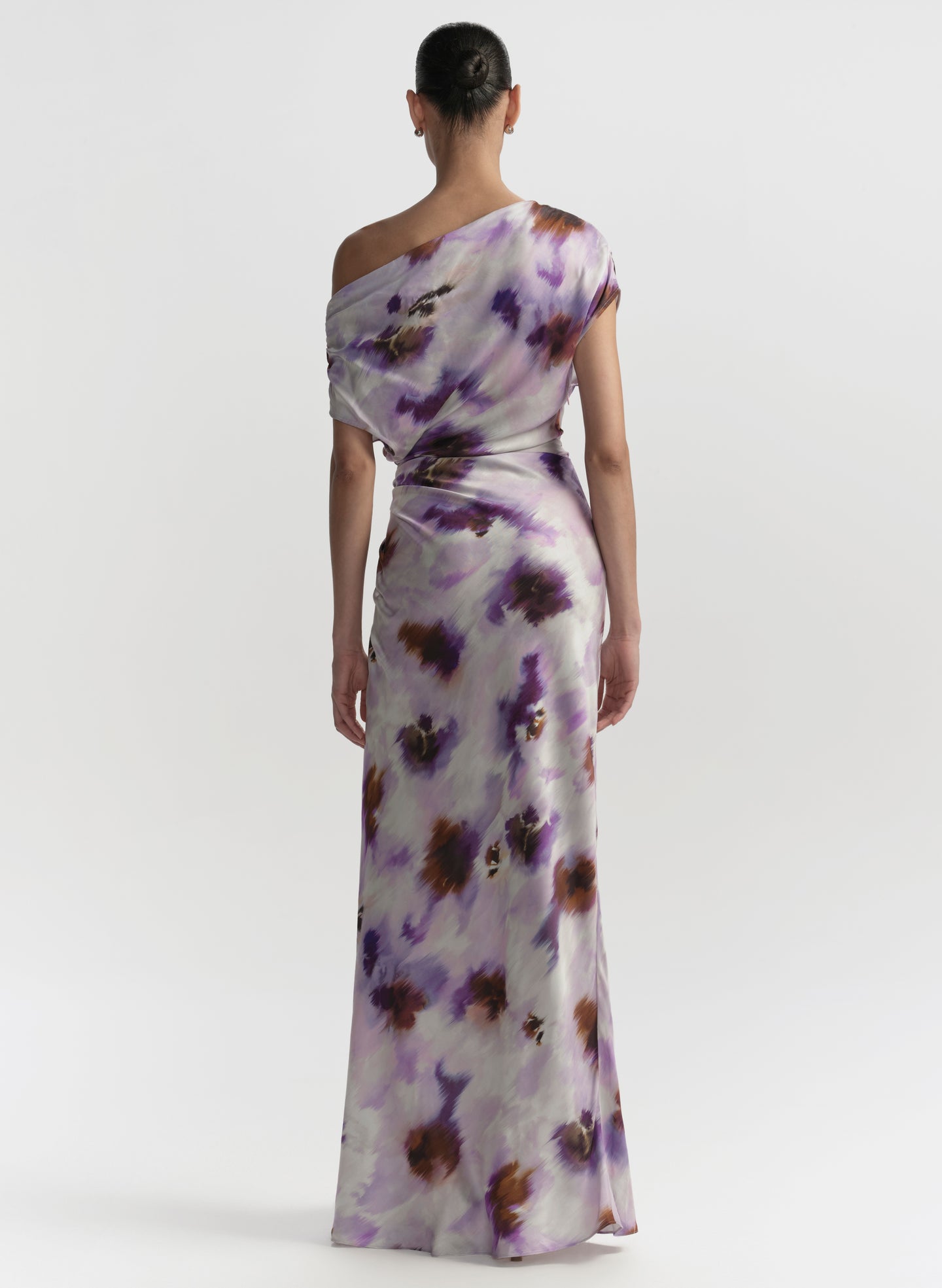 Woman wearing a one-shoulder floral dress on a white background