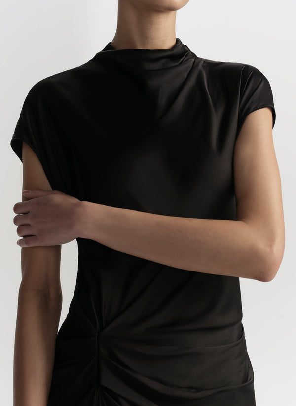 Person wearing a black dress against a light gray background