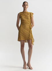 Woman wearing a mustard yellow lace dress on a white background