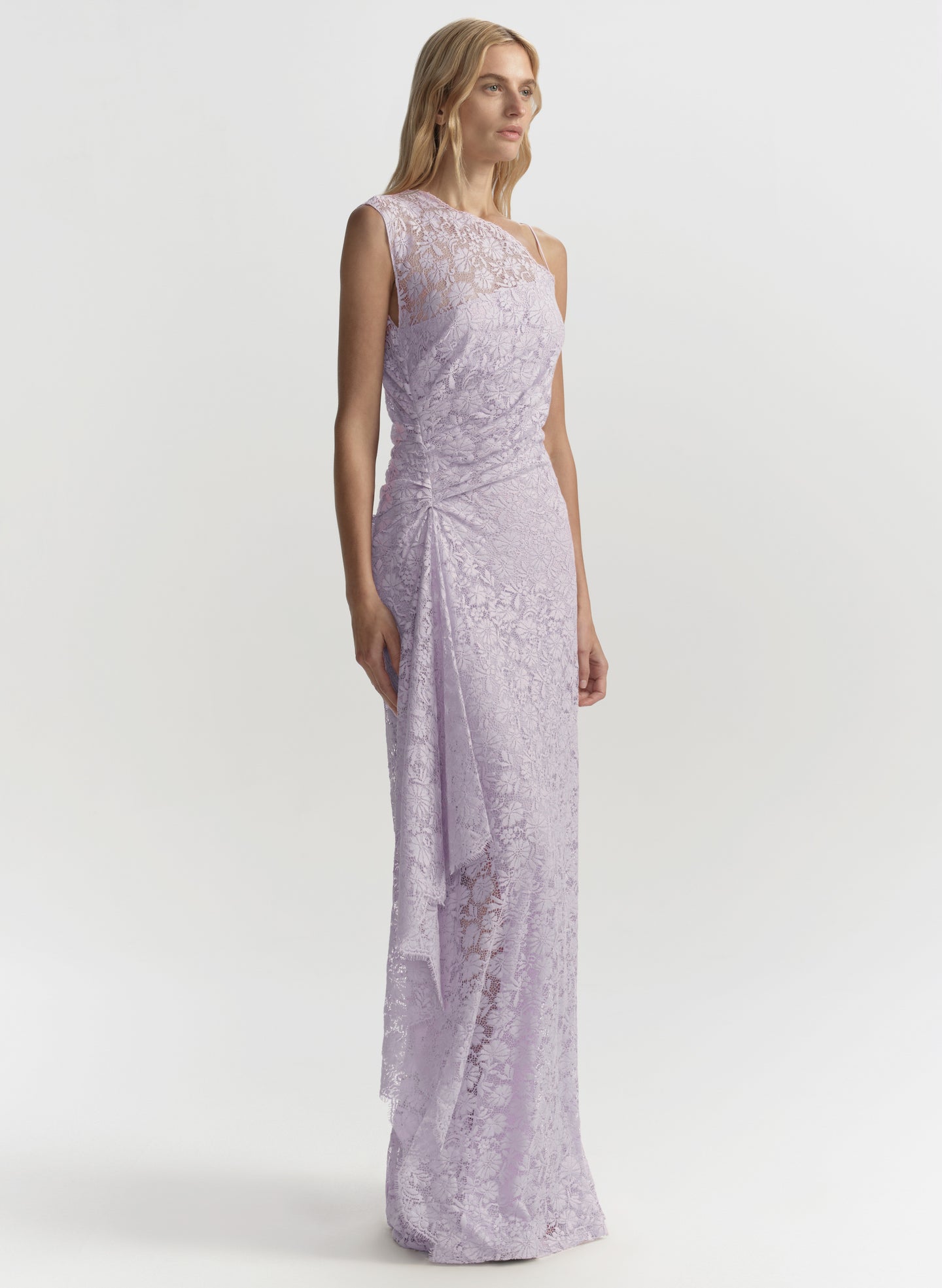 Woman wearing a long, light purple lace dress on a white background