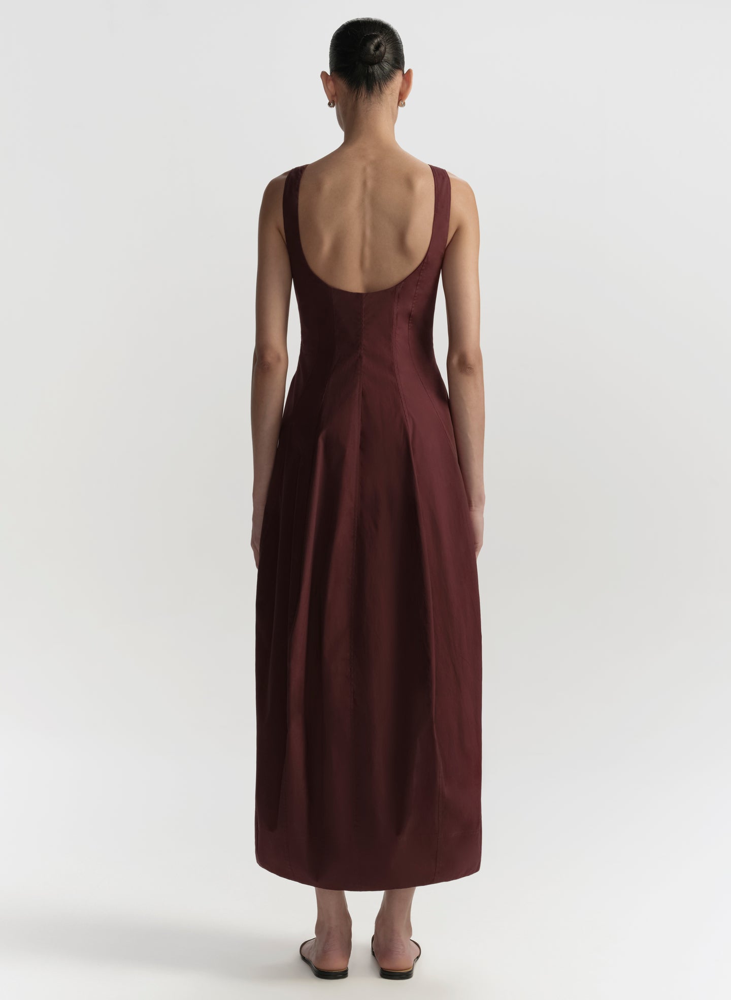 Woman wearing a brown dress with an open back on a white background