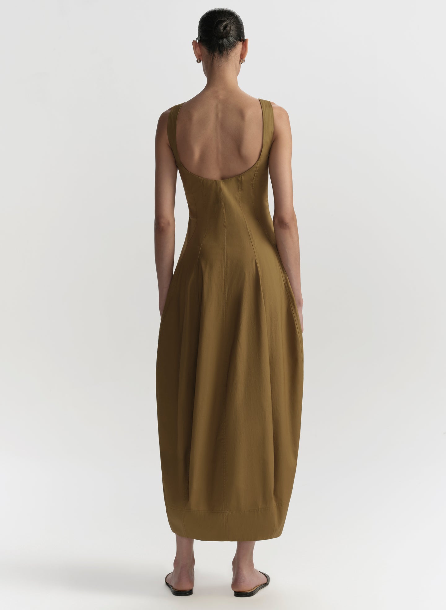 Woman wearing a long brown dress with a plain white background