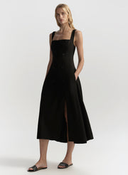 Woman wearing a black sleeveless dress with a slit on a white background