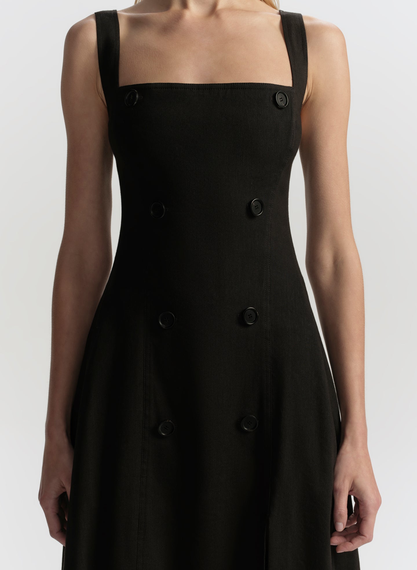 Black dress with button details on a white background