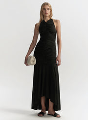 Woman wearing a black dress holding a clutch on a white background