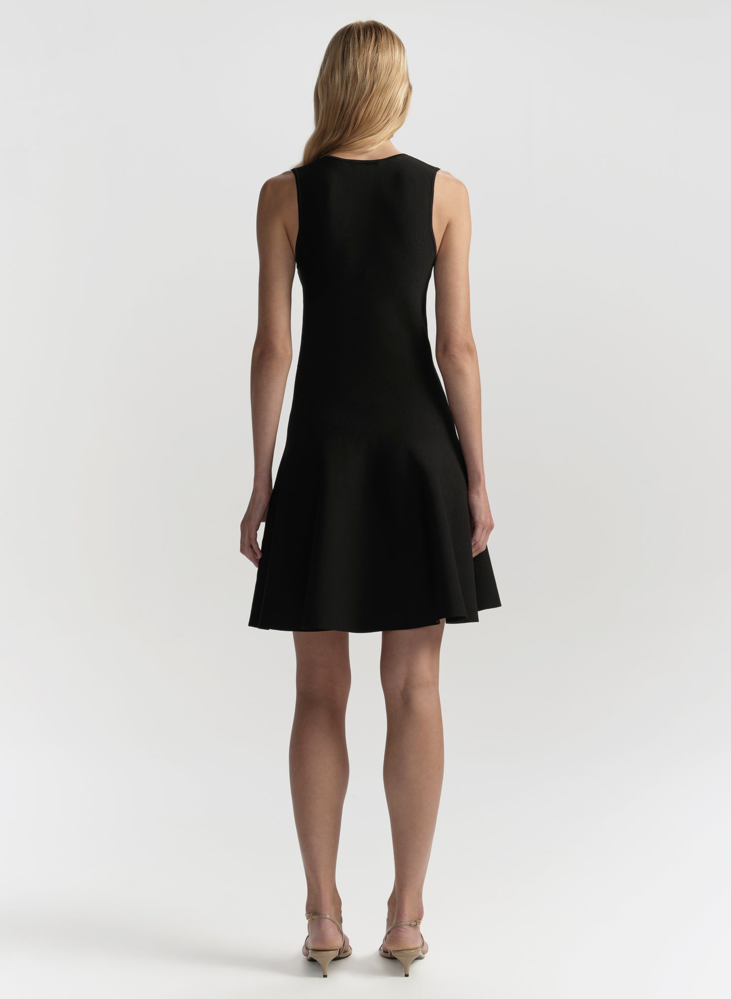 Black sleeveless dress worn by a model on a white background