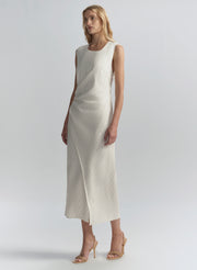 Woman wearing a white sleeveless dress on a plain background