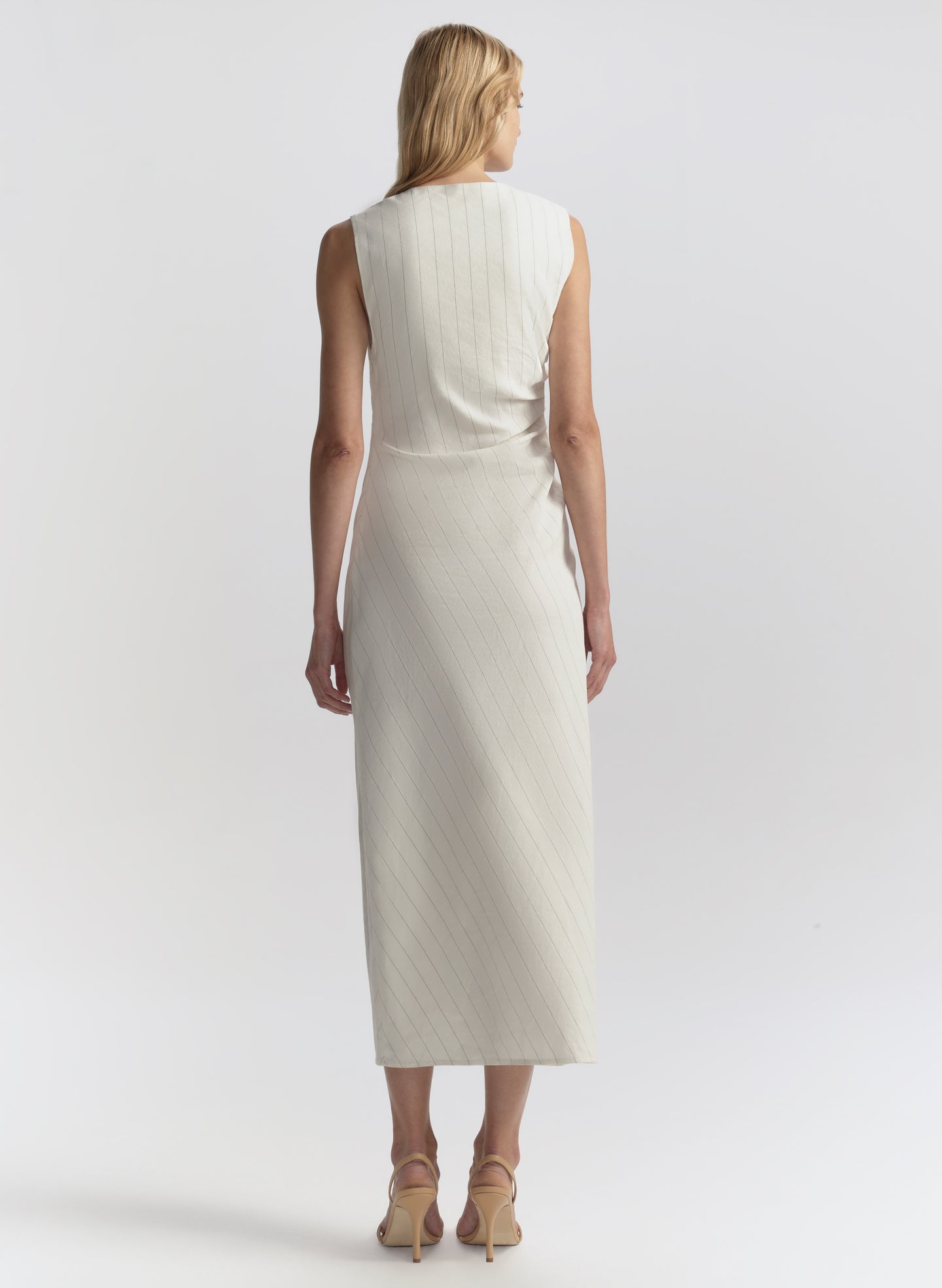 Woman wearing a white sleeveless dress against a plain background