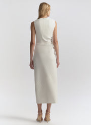 Woman wearing a white sleeveless dress against a plain background