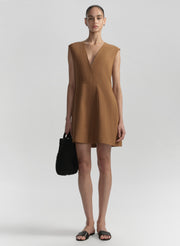 Woman wearing a brown dress holding a black handbag on a white background