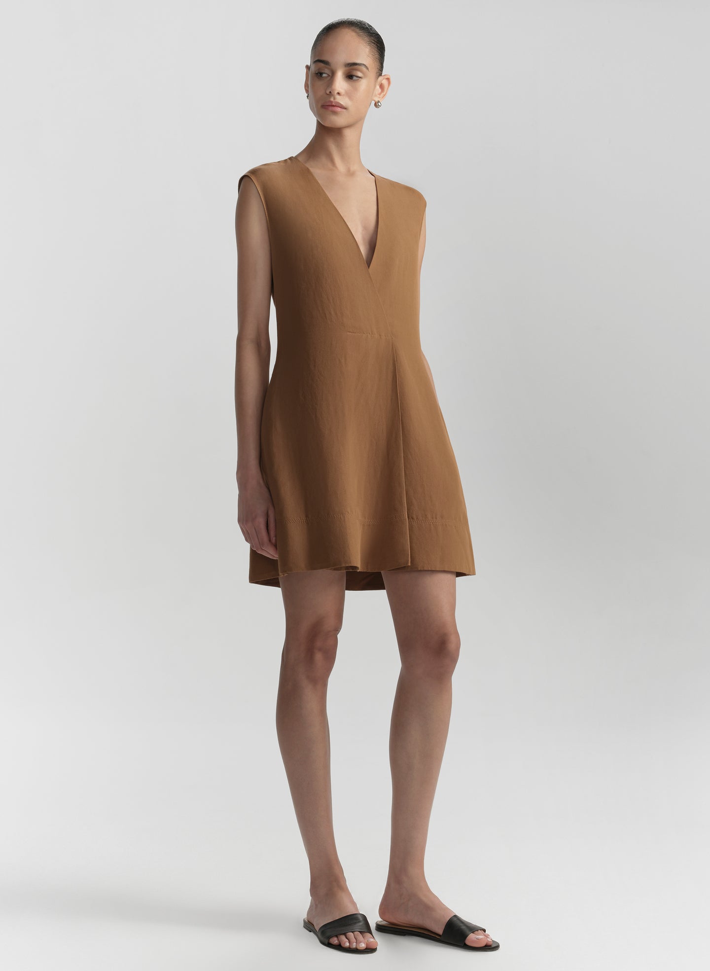 Woman wearing a brown sleeveless dress on a light gray background