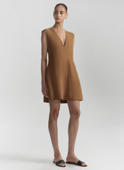 Woman wearing a brown sleeveless dress on a light gray background